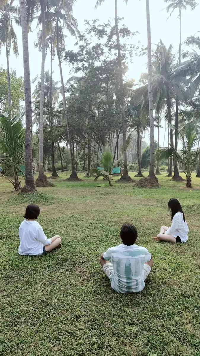 Three guests meditating on the grass in the coconut grove