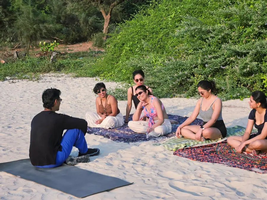 Guests in a beachside circle at golden hour, Sai Island retreat